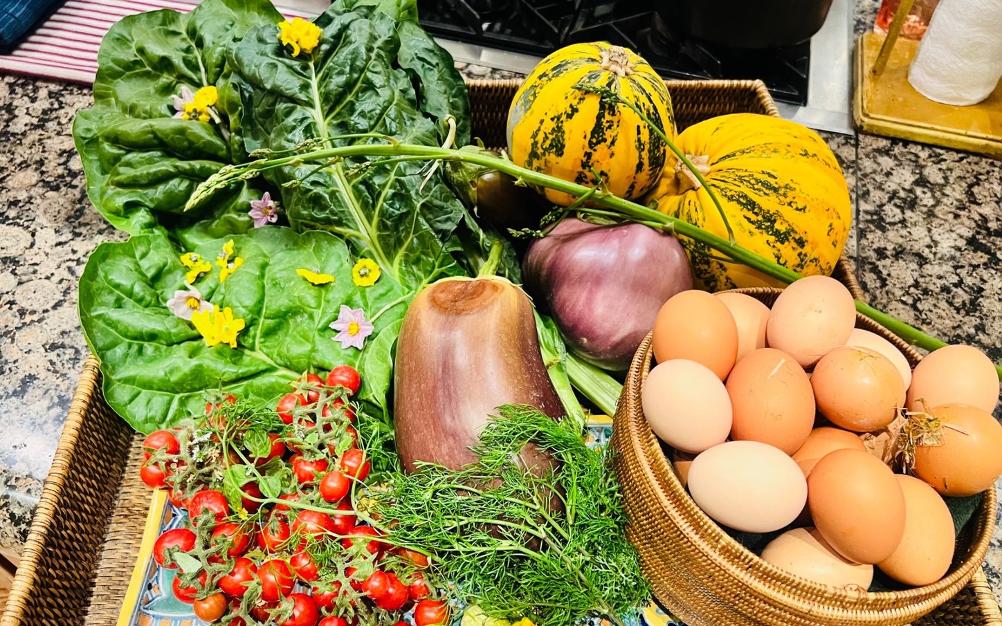 A Baja market haul — chard, squash, farm eggs and tomatoes — laid out before a villa dinner in Los Cabos